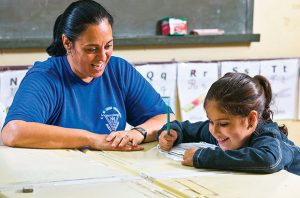 Adaptada à escola, a pequena Mariana escreve com o auxílio da professora Mara